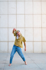 Young man barefoot, with dyed hair is dancing contemporary dance