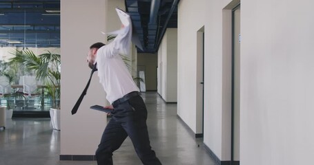 Happy employee celebrating work promotion. Ecstatic office worker celebrating professional success. Overjoyed young man who just nailed important presentation is having fun and dancing in office hall