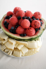A plate with watermelon, cantaloupe, blackberry and blueberry on a white background.