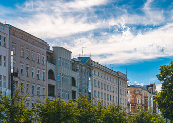 Old tenement houses on the street in the city against the blue summer sky. urban landscape © Adam