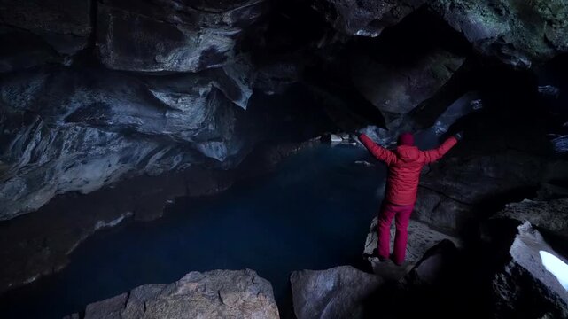 A young man visiting Grjotagja volcanic cave with incredibly blue and very hot hot springs near Lake Myvatn, Iceland