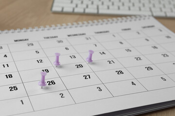 Timetable. Calendar page and drawing pins on table, closeup