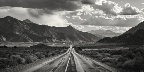 A black and white photograph of a winding road surrounded by mountains, suitable for use in travel or adventure-themed projects