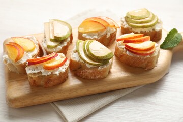 Delicious ricotta bruschettas with pears and apricots on white wooden table, closeup