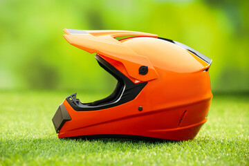 Orange motorcycle helmet with visor on green grass