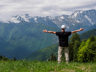 A man with outstretched arms against the background of majestic mountains, personifying freedom,...