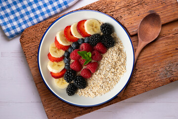 Delicious and healthy bowl of oatmeal with red fruits, raspberries, blueberries, strawberries and banana.
