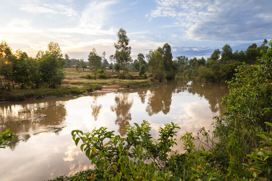 The sun sets over a peaceful, African landscape along the banks of a river. River Nzoia in western Kenya. 
