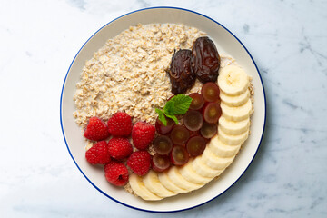 Delicious and healthy bowl of oatmeal with raspberries, dates, grapes and banana.