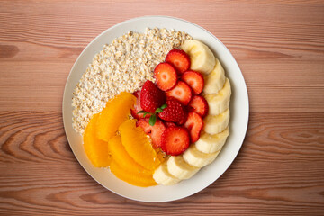 Delicious and healthy bowl of oatmeal with orange, strawberry and banana.