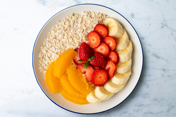 Delicious and healthy bowl of oatmeal with orange, strawberry and banana.