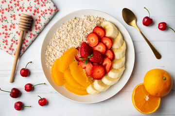 Delicious and healthy bowl of oatmeal with orange, strawberry and banana.