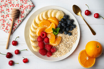 Delicious and healthy bowl of oatmeal with tangerine, banana, blueberries and raspberries.