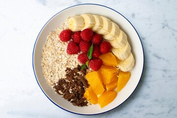 Delicious and healthy bowl of orange, chocolate, raspberries, and banana oats.