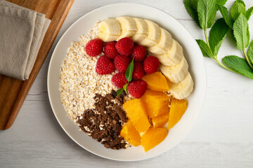 Delicious and healthy bowl of orange, chocolate, raspberries, and banana oats.
