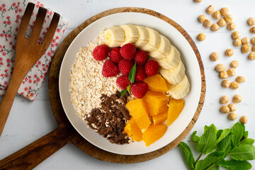 Delicious and healthy bowl of orange, chocolate, raspberries, and banana oats.