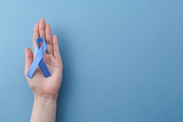 Woman with blue awareness ribbon on color background, top view. Space for text