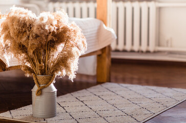 Pampas Grass in a White Jug by Bed. Rustic pampas grass in a white jug, placed beside a cozy bed....