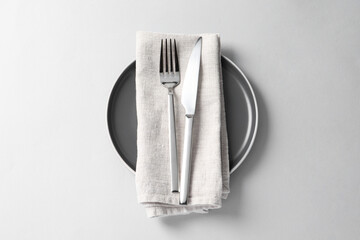 Stylish silver cutlery, plate and napkin on white background, top view