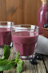 Tasty fresh acai juice in glasses with berries and mint on wooden table, closeup
