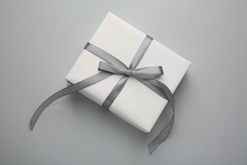 Gift box with satin bow on grey background, top view