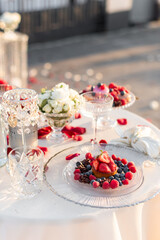Close up selective focus desserts with sweet fresh berries and empty glasses. Summer romantic evening under the open sky. Delicious fruit snacks and drinks outdoors.