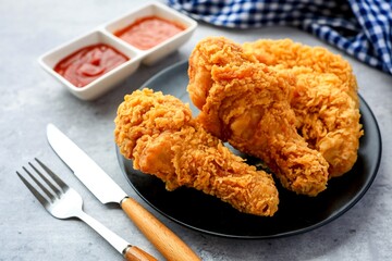 Fried chicken on a black plate with tomato sauce and chili sauce,	