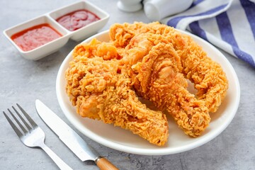 Fried chicken on a white plate with tomato sauce and chili sauce,	