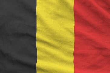 Belgium flag depicted on folded wavy fabric of old cloth close up