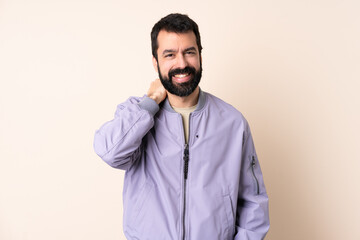 Caucasian man with beard wearing a jacket over isolated background laughing