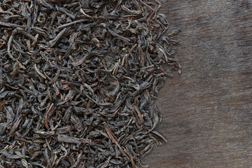 Long black tea on a dark wooden background. Top view of dried tea leaves. Tea composition