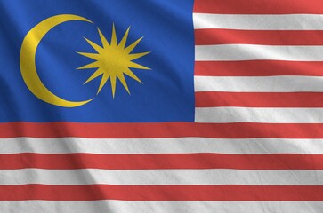 Malaysia flag depicted on folded wavy fabric of old cloth close up