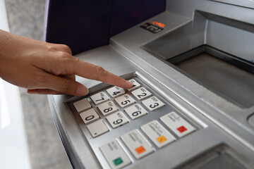 Close up of woman hand entering PIN code into an ATM bank machine.