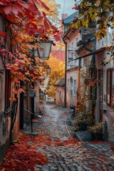Fototapeta premium A scenic view of a cobblestone street surrounded by autumn foliage and buildings
