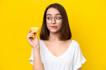 Young Ukrainian woman isolated on yellow background holding a donut