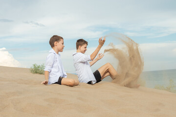 Two Boys Playing with Sand on Beach: Childhood Adventure and Time Metaphor by Ocean Shore