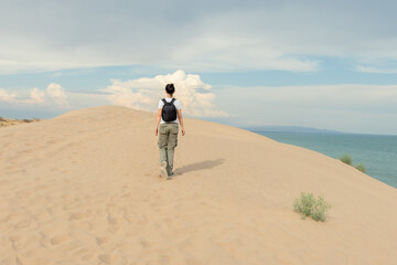 Fototapeta premium Solo Traveler Exploring Sand Dunes Overlooking Ocean: Adventure and Discovery on Coastal Desert Landscape