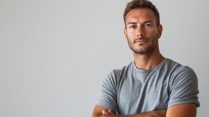 Fototapeta premium A man with a serious expression, arms crossed against a white background, embodying strength and determination