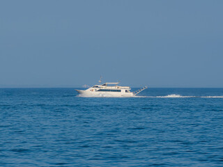 White yacht cruising on a clear blue sea