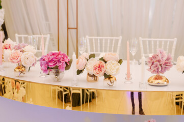Table decoration from pink and  white roses and  candle sticks on the table at wedding  reception.