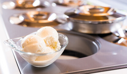Glass dessert bowl with vanilla ice cream on the table in the display case for distribution