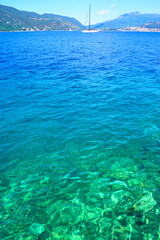 Sailing trips in picturesque places of the Mediterranean Sea: landscape with water of bright turquoise and blue color, mountains and a sailboat on the horizon. Summer holidays in the Bay of Kotor
