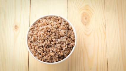 buckwheat porridge in a round white plate on a wooden table.