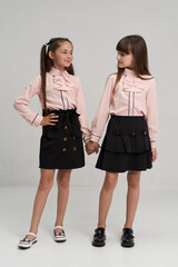 A girl of European origin in a school uniform on a white background. Smiling at the camera