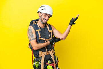 Young caucasian rock climber man isolated on yellow background extending hands to the side for inviting to come