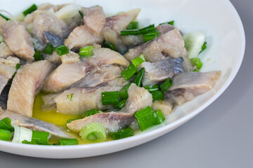 Sliced pickled atlantic herring with chopped green onion close-up