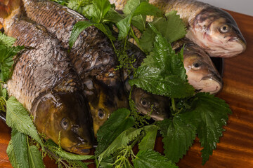Raw cleaned prepared carps and grass carp mixed with nettles