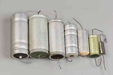 Old axial-lead capacitors in round housings on gray surface
