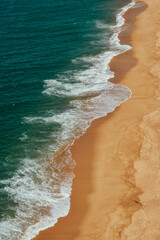 Fotograf&iacute;a de la playa de Nazar&eacute; con el agua y la arena sin gente, Portugal.