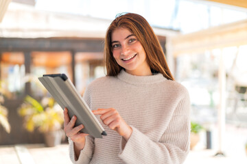 Young pretty caucasian woman touching the tablet screen with happy expression